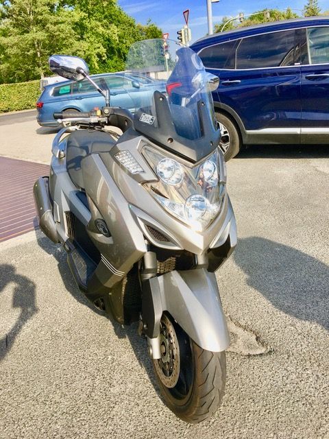 Ein Roller mit Windschutzscheibe steht auf einem Parkplatz