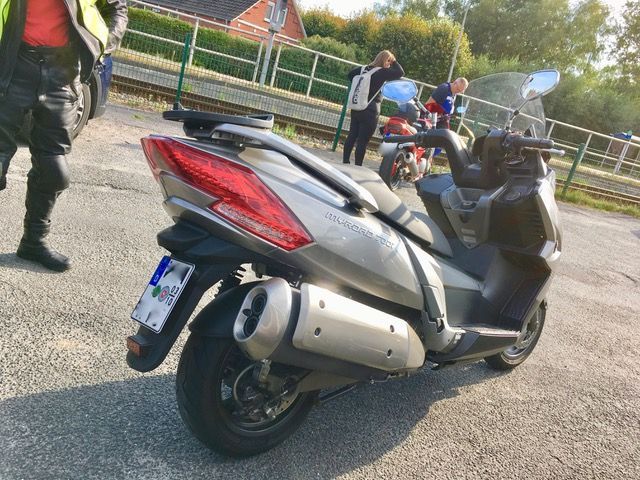 Ein Motorroller steht am Straßenrand auf einem Parkplatz.