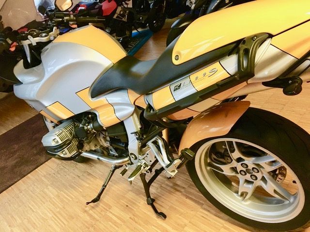 Ein gelb-weißes Motorrad ist auf einem Holzboden geparkt