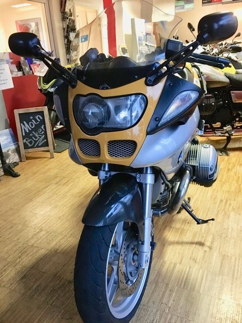 Ein Motorrad steht vor einem Schild mit der Aufschrift „Moin“