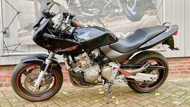 Vor einem Backsteingebäude parkt ein schwarzes Motorrad.