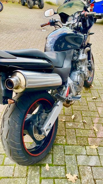 Auf einem gepflasterten Gehweg ist ein schwarzes Motorrad geparkt.