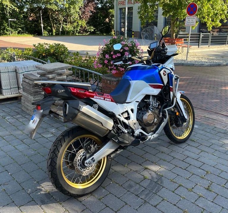 Ein blau-weiß-rotes Motorrad ist auf einem gemauerten Bürgersteig geparkt