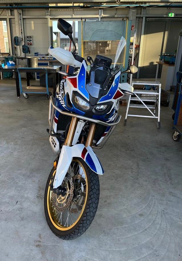 In einer Garage steht ein blau-weiß-rotes Motorrad.