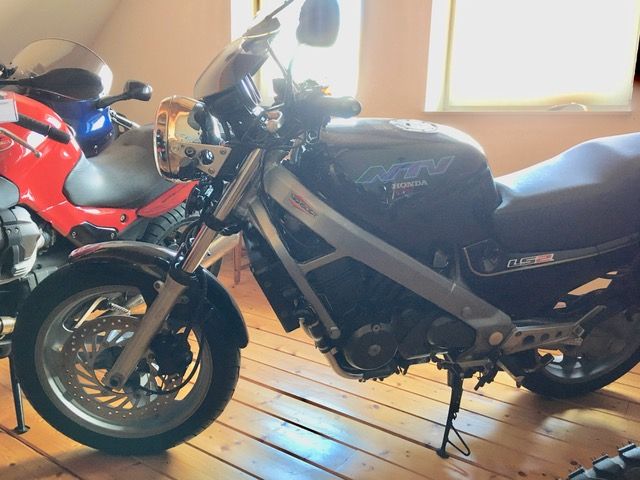 Zwei Motorräder sind nebeneinander auf einem Holzboden geparkt