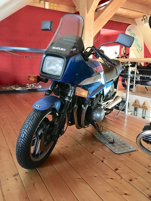 Ein blaues Suzuki-Motorrad ist auf einem Holzboden geparkt