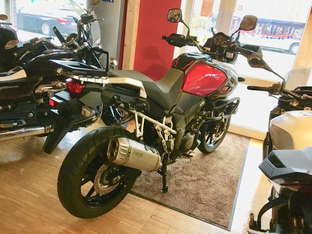 Ein rotes Motorrad ist in einem Raum mit anderen Motorrädern geparkt