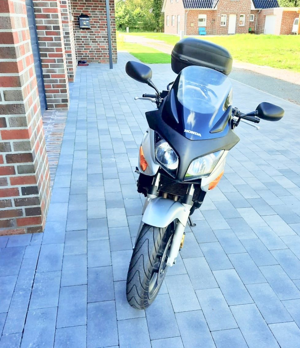 Ein Motorrad ist auf einem gemauerten Gehweg vor einem Backsteingebäude geparkt