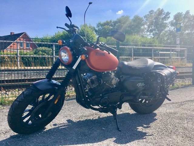 Ein rot-schwarzes Motorrad ist am Straßenrand geparkt.