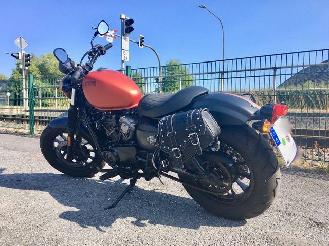 Ein rot-schwarzes Motorrad ist am Straßenrand geparkt.
