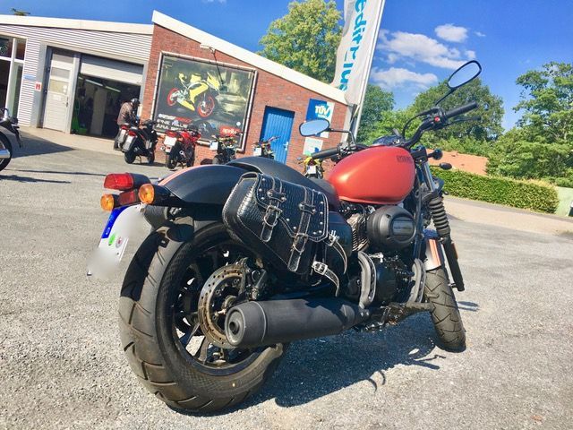 Ein rot-schwarzes Motorrad steht vor einem Gebäude