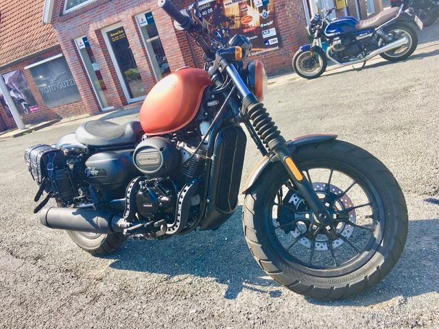 Ein Motorrad ist am Straßenrand vor einem Gebäude geparkt.