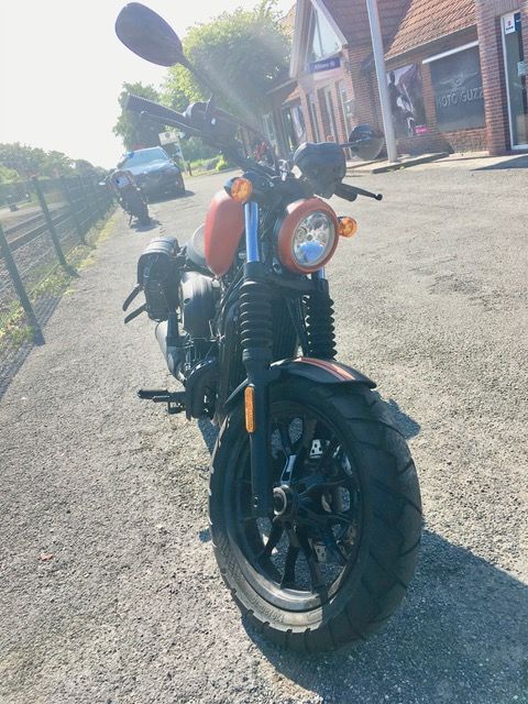 Ein Motorrad ist am Straßenrand vor einem Gebäude geparkt.