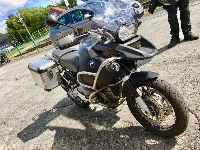 Ein Mann steht neben einem am Straßenrand geparkten Motorrad.