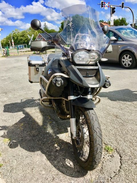 Ein Motorrad steht auf einem Parkplatz neben einem Auto