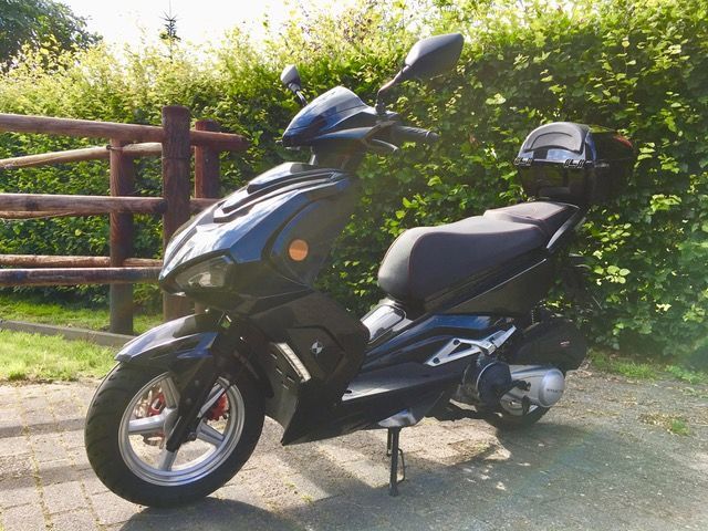 Ein schwarzer Roller steht vor einem Zaun