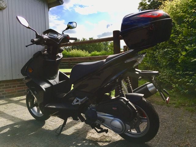 Ein schwarzer Roller steht vor einem weißen Gebäude