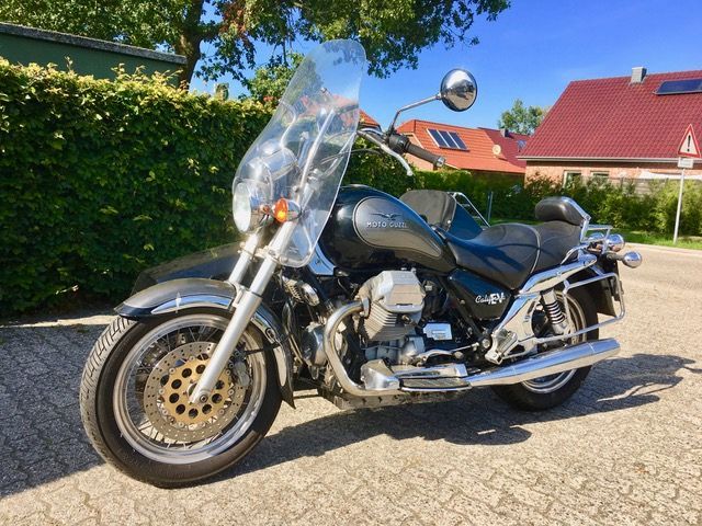 Vor einem Haus ist ein Motorrad mit Windschutzscheibe geparkt.