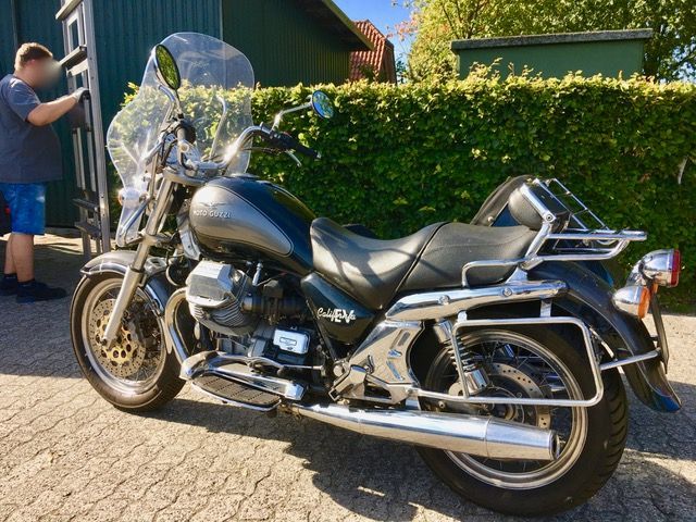 Ein Mann steht neben einem Motorrad mit einer Windschutzscheibe