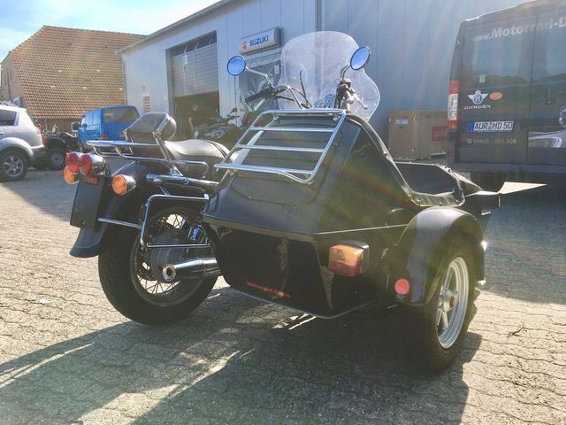 Vor einem Gebäude ist ein Motorrad mit Beiwagen geparkt.