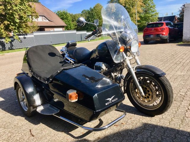 Ein schwarzes Motorrad mit Beiwagen steht am Straßenrand.