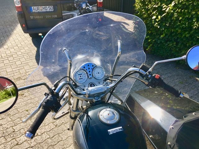 Ein Motorrad mit Windschutzscheibe ist neben einem Auto geparkt.