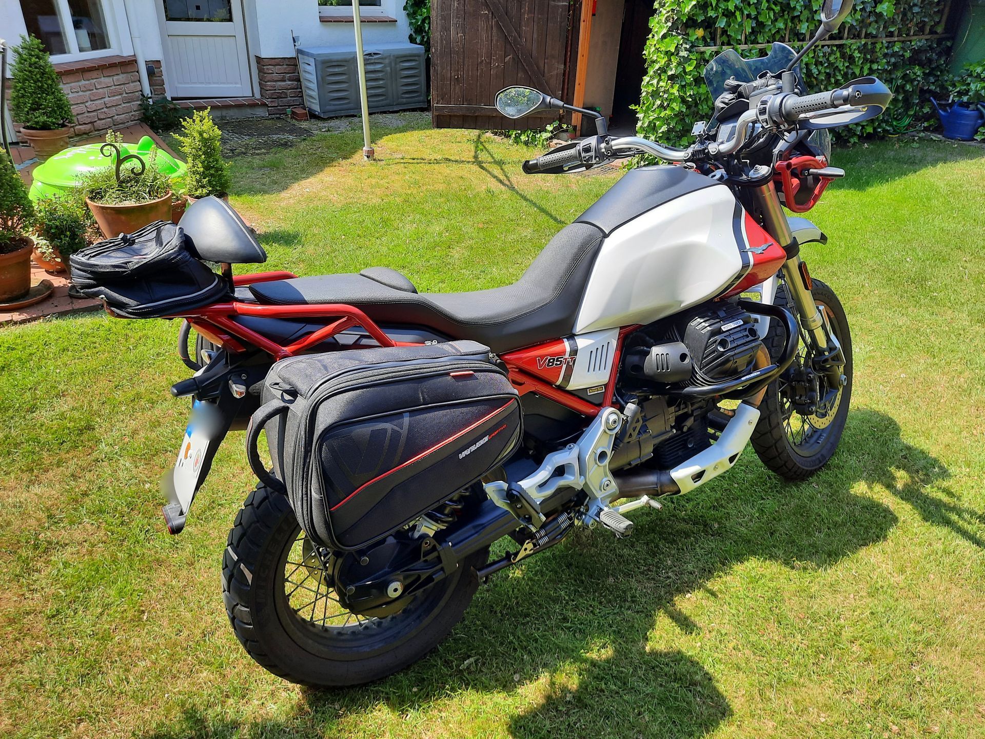 Ein Motorrad ist im Gras vor einem Haus geparkt.