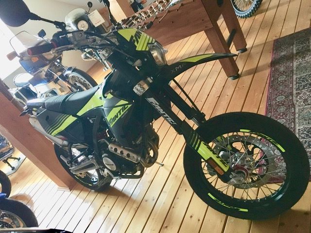 Ein gelb-schwarzes Motorrad ist auf einem Holzboden geparkt