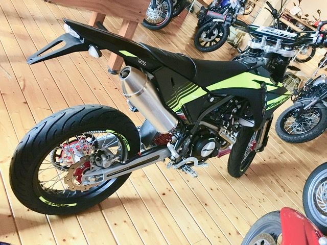 In einem Ausstellungsraum steht ein Motorrad auf einem Holzboden.