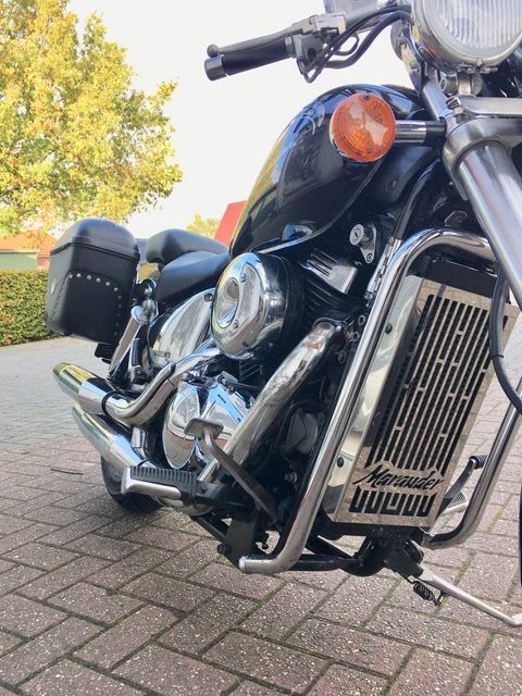 Auf einem gepflasterten Gehweg ist ein schwarzes Motorrad geparkt.