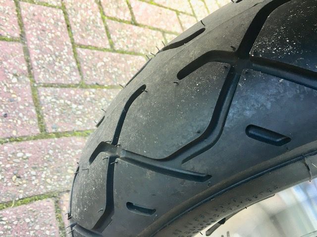 Eine Nahaufnahme eines Motorradreifens auf einem gemauerten Bürgersteig