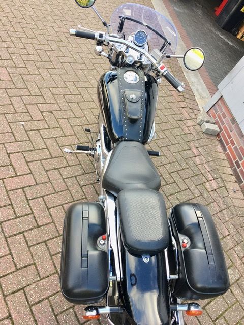 Auf einem gepflasterten Gehweg ist ein schwarzes Motorrad geparkt.