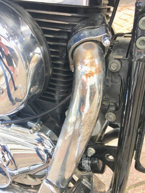 Eine Nahaufnahme eines Motorradmotors und eines Auspuffrohrs.