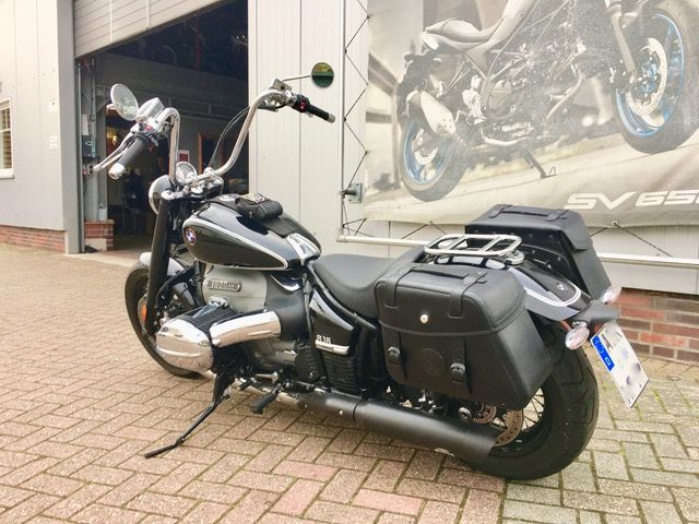 Vor einer Garage parkt ein schwarzes Motorrad.