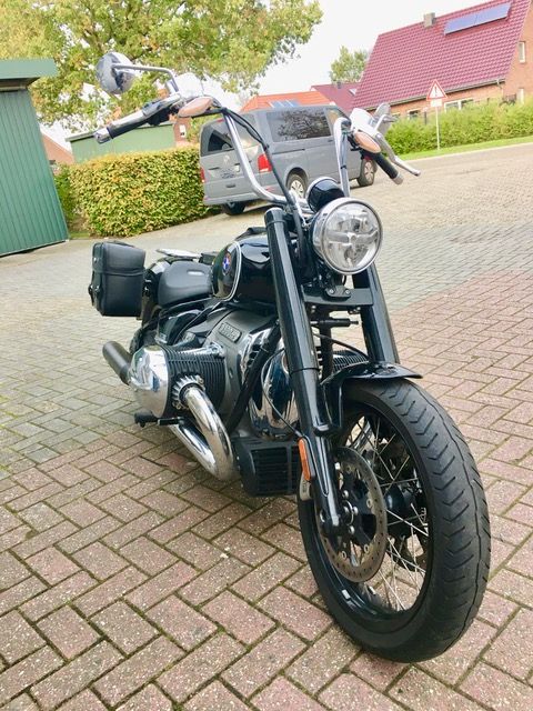 Auf einer gepflasterten Auffahrt ist ein schwarzes Motorrad geparkt.