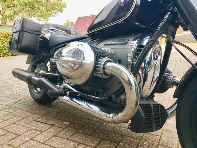 Auf einer gepflasterten Auffahrt ist ein schwarzes Motorrad geparkt.