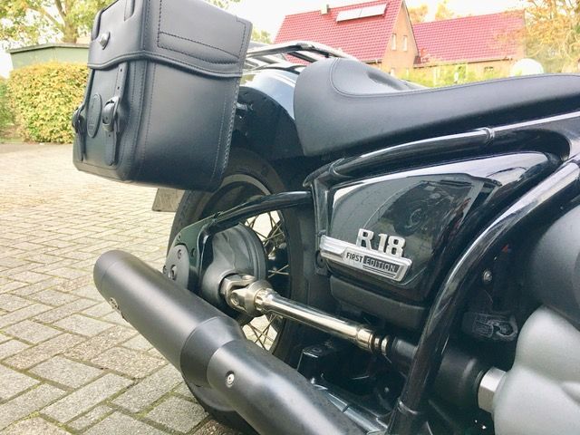Auf einer gepflasterten Auffahrt vor einem Haus ist ein schwarzes Motorrad geparkt.