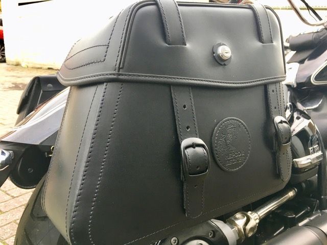 Auf der Rückseite eines Motorrads ist eine schwarze Satteltasche aus Leder befestigt.