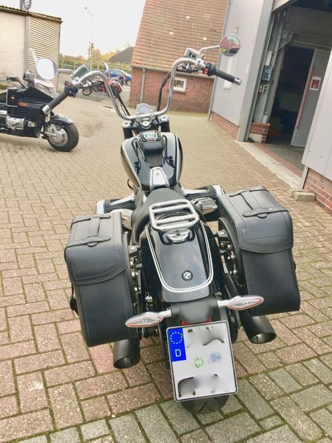 Ein Motorrad ist auf einem gepflasterten Gehweg vor einer Garage geparkt.