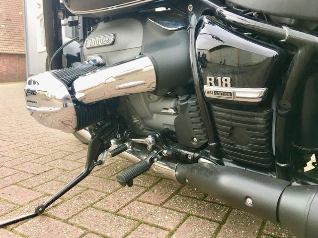 Auf einem gepflasterten Gehweg ist ein schwarzes Motorrad geparkt.
