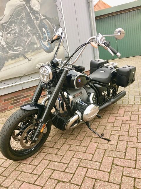 Ein schwarzes Motorrad ist auf einem gepflasterten Gehweg vor einem Gebäude geparkt.