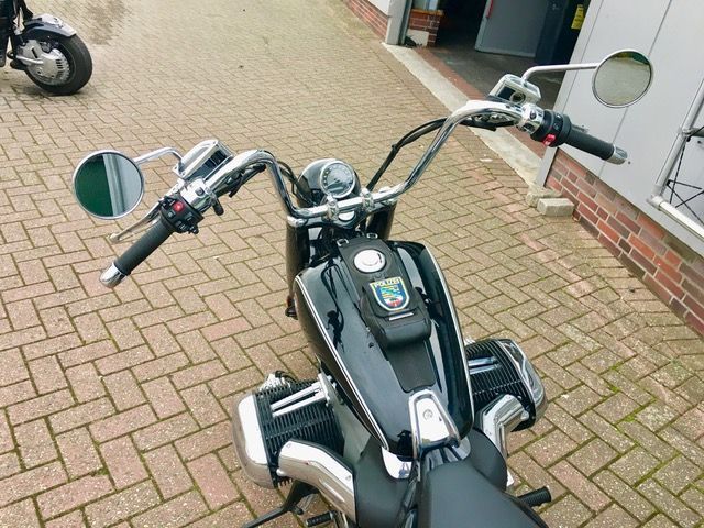 Auf einem gepflasterten Gehweg ist ein schwarzes Motorrad geparkt.