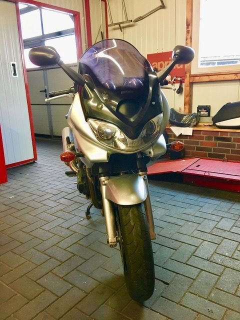 Ein Motorrad mit einer violetten Windschutzscheibe steht in einer Garage