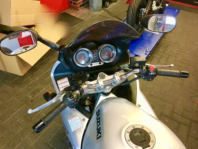 Ein silbernes Suzuki-Motorrad steht in einer Garage