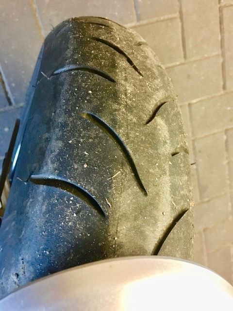 Eine Nahaufnahme eines Motorradreifens auf einem Ziegelboden.