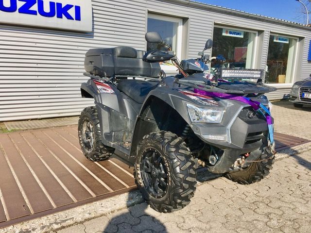 Vor einem Gebäude ist ein Suzuki-ATV geparkt.