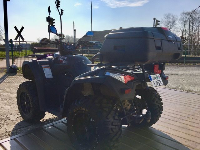 Ein schwarzes Geländefahrzeug mit einer großen Kiste auf der Rückseite ist am Straßenrand geparkt.