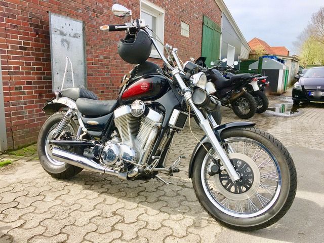 Vor einem Backsteingebäude parkt ein Motorrad mit einem Helm auf dem Lenker.