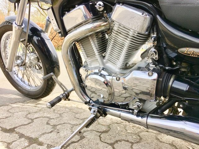 Eine Nahaufnahme des Motors eines auf einem Bürgersteig geparkten Motorrads.