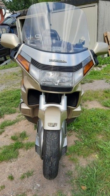 Gold- und silberfarbenes Honda Goldwing-Motorrad, im Freien geparkt, Vorderansicht. Mit großer Windschutzscheibe, quadratischen Scheinwerfern und dickem Vorderreifen.